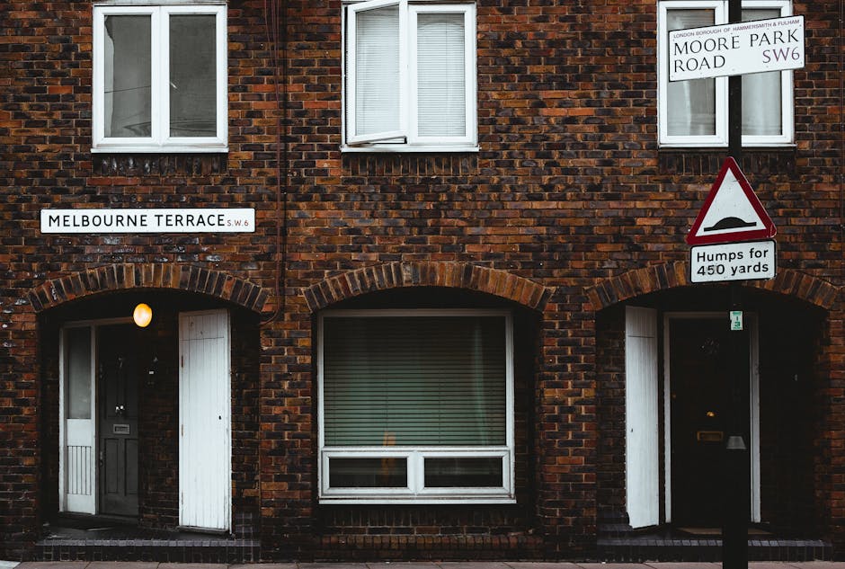 The image depicts the front of a two-storey brick residential building located on Melbourne Terrace, with a street sign indicating the location. The building's facade is constructed from dark red and 